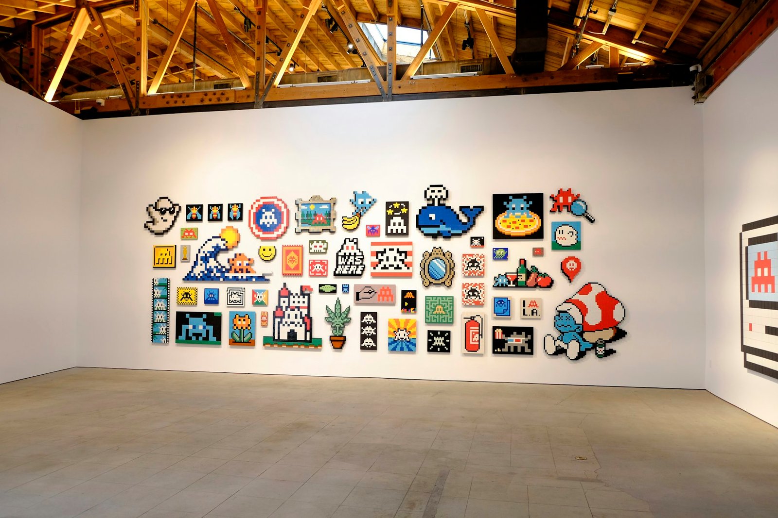 A white gallery wall hung with many small pixel works.