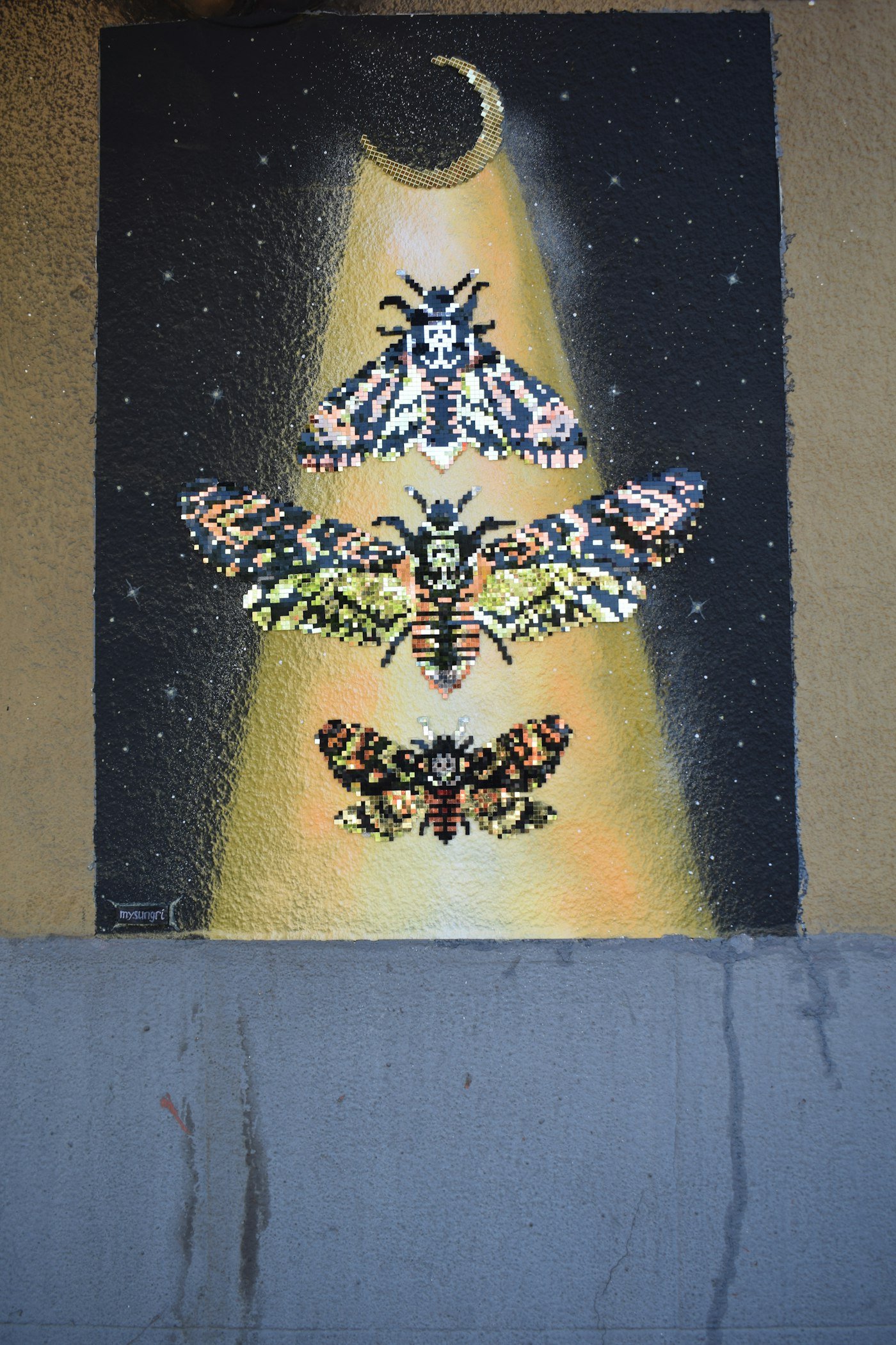 Three pixel moths under a crescent moon.